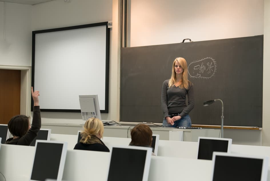 מרצה עומדת ליד לוח בכיתה חכמה